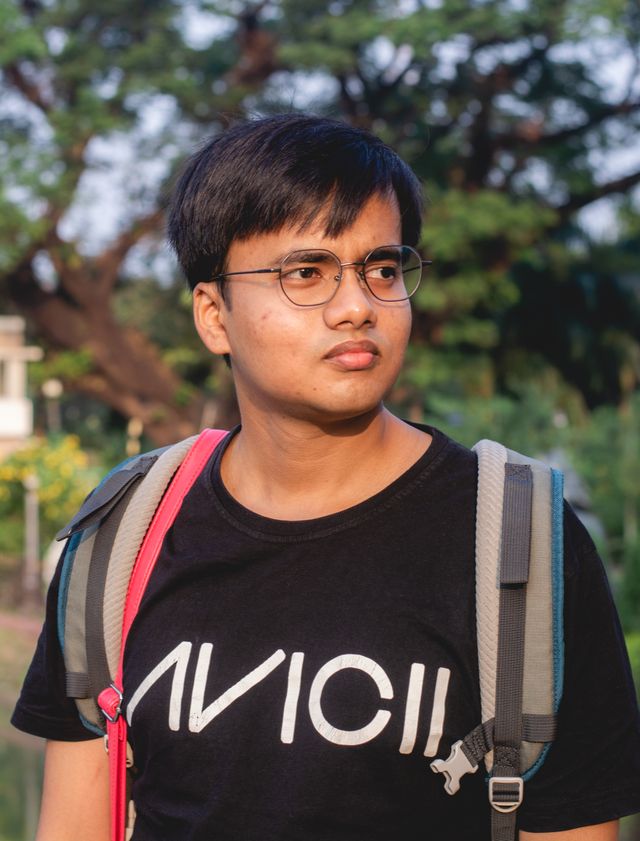 Portrait of a young man in a shirt smiling at the camera outdoors