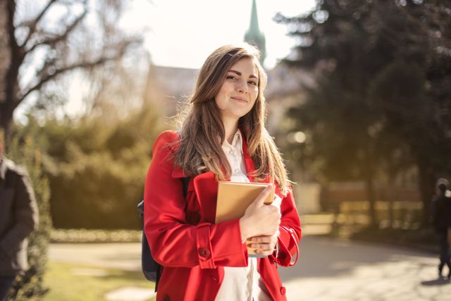 Portrait of a young woman student holding books on a university campus